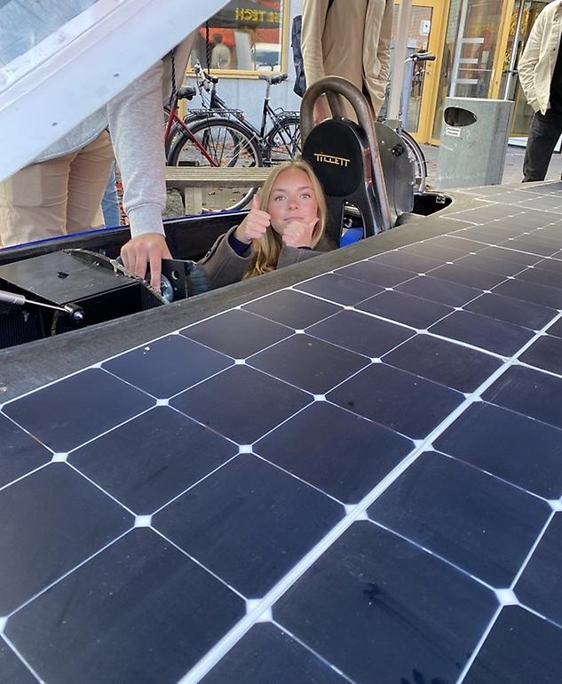 elev i solpanelstyrd bil som gör tummen upp mot kameran.