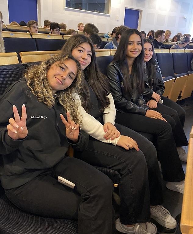 Fyra kvinnliga elever som sitter i en aula och tittar mot kameran. 